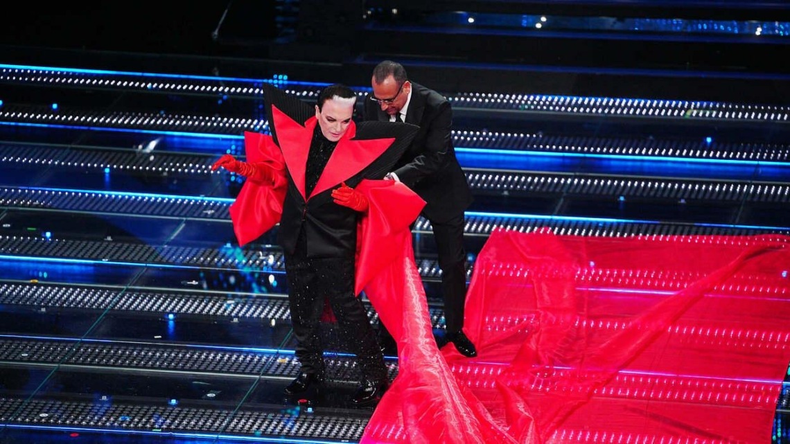 Cristiano Malgioglio, co-conduttore al fianco di Carlo Conti, scende la scalinata dell'Ariston con un lunghissimo strascico di colore rosso